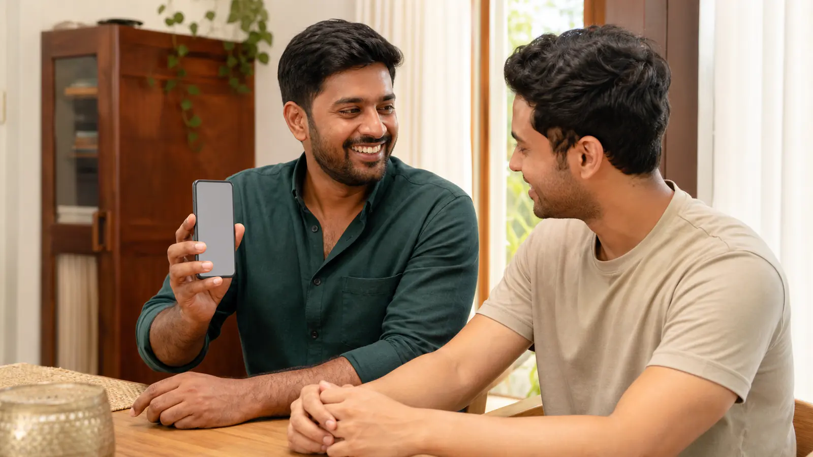 Two Indian adults sharing a referral from a mobile phone at home